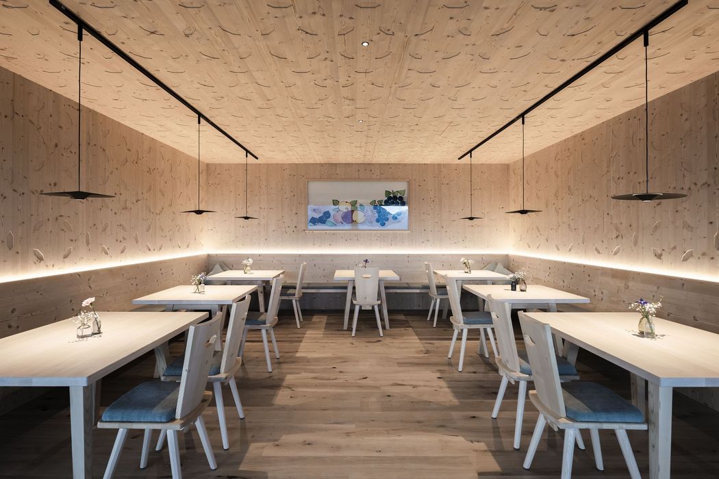 Moderner, minimalistisch eingerichteter Raum mit Holzvertäfelung, Holztischen und -stühlen, dezenter Beleuchtung und Blumenvasen auf den Tischen. Moderner, minimalistisch eingerichteter Raum mit Holzvertäfelung, Holztischen und -stühlen, dezenter Beleuchtung und Blumenvasen auf den Tischen.